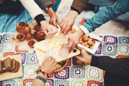 Theres enough for everyone. a group of unrecognizable peoples hands taking food from a plate at a picnic outside during the day.の写真素材