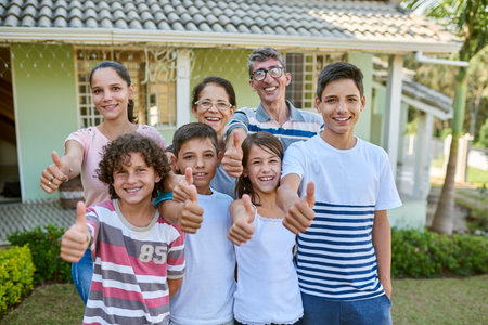 Whatever the question, family will always be the answer. Portrait of a happy multi generational family standing together in their backyard and giving thumbs up.の写真素材