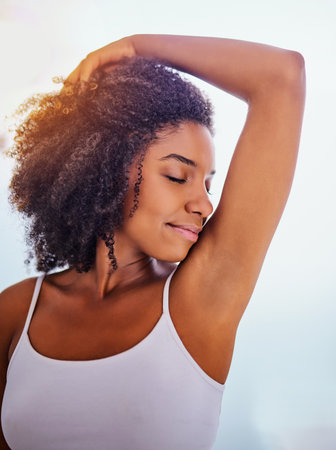 Ive found my new favourite deodorant. an attractive young woman smelling her armpits during her morning beauty routine.の写真素材