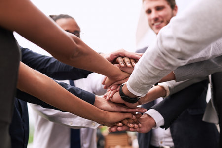 Lets do this. Closeup shot of an unrecognizable group of businesspeople joining their hands in a...