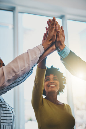 Winning is the best. a group of businesspeople high fiving in an office.