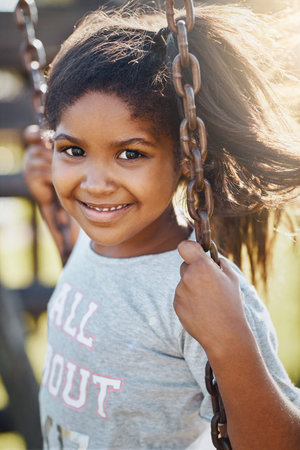 Wanna see how good my swinging skills are. Portrait of an adorable little girl playing on a swing at...