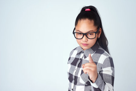 Dont go there. Studio portrait of a cute young girl pointing her finger with attitude against a gray background.の写真素材