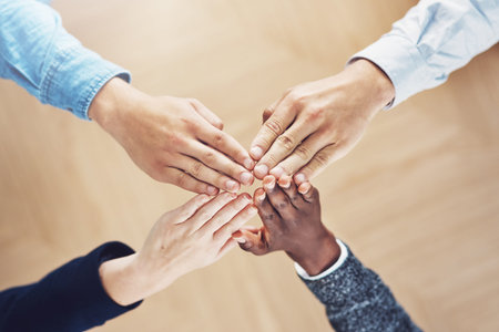 Work as one, get it done. High angle shot of a group of unidentifiable businesspeople joining their...