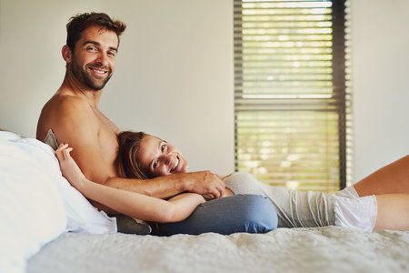 It doesnt get much better than this. a happy young couple relaxing in bed together.の写真素材