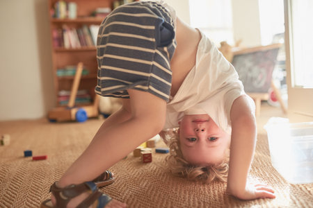 Kids see the fun from every angle of life. an adorable little boy trying to do a handstand at home.の写真素材