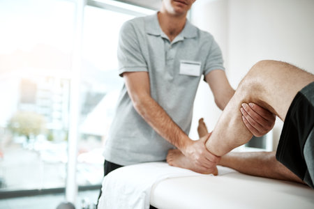 The pain will go away if you do these movements regularly. an unrecognizable male physiotherapist helping a client with leg exercises whos lying on a bed.の写真素材