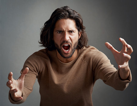 You better run. Studio shot of a young man screaming in anger against a gray background.の写真素材