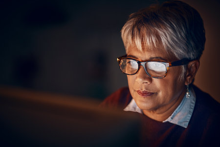 Pushing her effort into some extra hours. a mature businesswoman working late in an office.の写真素材