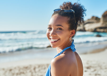Lets go make some awesome summer memories. Portrait of a beautiful young woman enjoying a summers day at the beach.の写真素材