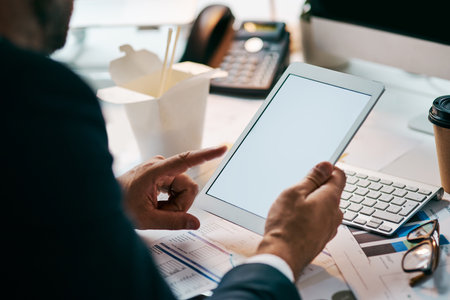He has full control in his hands. an unrecognizable businessman browsing on his digital tablet while being seated in the office during the day.の写真素材
