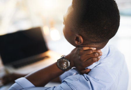 My neck has felt like this for a while now. a young unrecognizable businessman suffering from neck pains while trying to work in the office.の写真素材