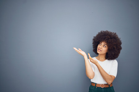 Afro woman, showing hands and advertising space on grey studio background for marketing mockup,...