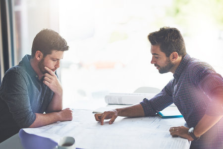 Theyre pros at redesigning any space. two young designers working on blueprints in an office.