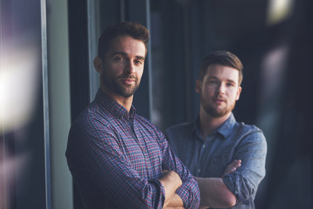 Excellence is what we strive for. Portrait of two confident young businessmen standing with their arms crossed.の写真素材