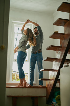 We make it look easy. an affectionate young couple at home dancing together.の写真素材