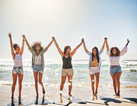 Bring on the good times. a group of cheerful friends holding hands on the beach.の写真素材