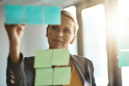 Planning is only the beginning. a mature corporate businesswoman planning on a glass wipe board.の写真素材