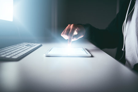 Touching the future. an unrecognizable man using a tablet while working late in the office.の写真素材