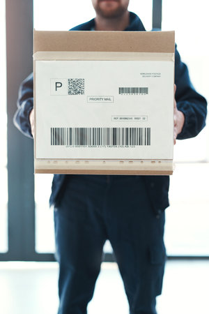 He always arrives bright and early on every delivery. an unrecognizable delivery man waiting in the lobby with a customers order.の写真素材