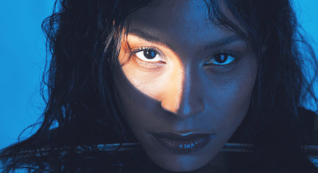Beauty, cosmetics and portrait of a model with a light reflection on her face in the studio....