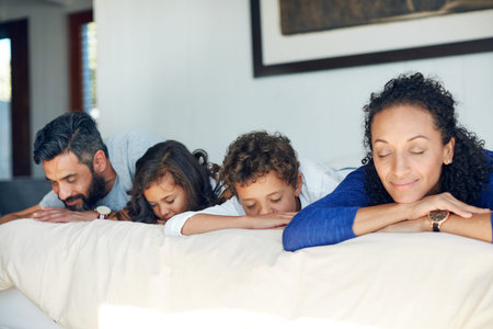 Close your eyes and just enjoy the weekend. a family lying down on a bed with their eyes closed at...