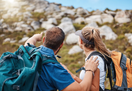 Hiking, couple and mountain in nature with rock, climbing and challenge for fitness, exercise and performance. Hand, man and woman looking up hill, hikers, morning and cardio workout adventureの写真素材