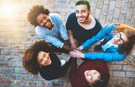 Well achieve our dreams together. High angle portrait of a diverse group of college friends standing outside with their hands in a huddle.の写真素材