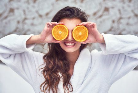 Oranges are here to brighten up the day. an attractive young woman holding up orange halves.の写真素材