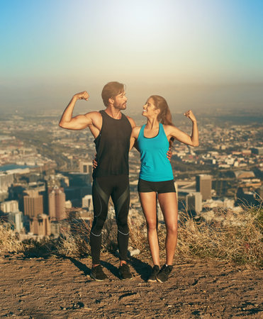 Be each others inspiration. a young couple flexing their muscles while out for a workout.の写真素材