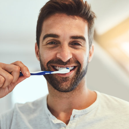 Keeping them pearly whites shinin. Cropped portrait of a handsome young man brushing his teeth in his bathroom at home.の写真素材