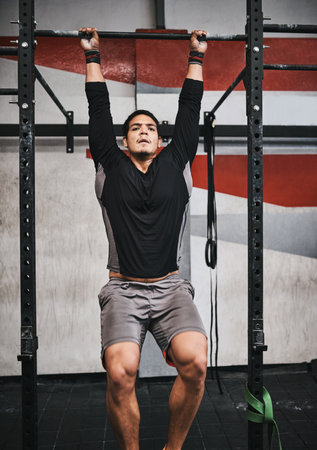 Working out my whole body. a young man doing pull ups in a gym.の写真素材