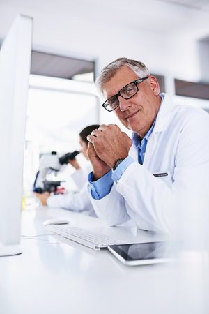 Anticipating their next big discovery. Portrait of a mature scientist working on a computer in a lab.の写真素材