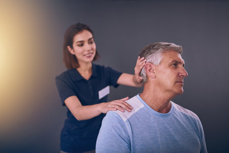 Look to the side for me. a young female physiotherapist treating a mature male patient.の写真素材