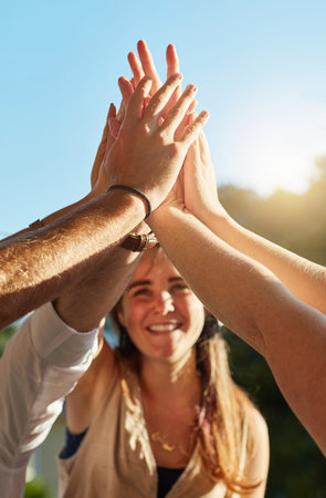 Friends through thick and thin. a group of happy young friends high fiving each other at an outdoor...