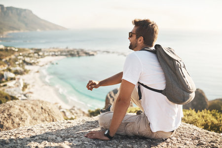 The perfect spot to check out the view. Full length shot of an unrecognizable young man taking in the views while hiking in the mountains.の写真素材