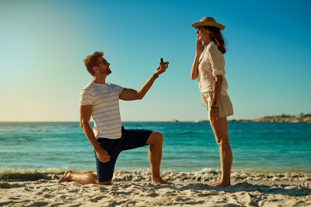 The perfect spot for a summer engagement. a young man proposing to his girlfriend at the beach on a summers day.の写真素材