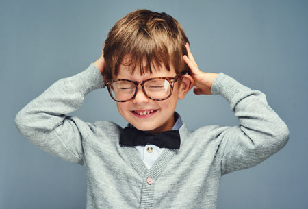 Knowledge overload. Studio portrait of an adorable little boy dressed smartly against a gray background.の写真素材