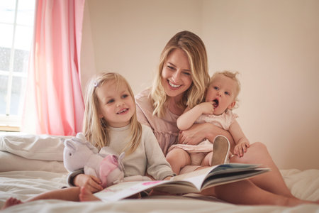 Its a time to learn and a time to bond. an adorable family of three reading a book together on the bed at home.の写真素材