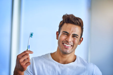 Keeping my smile at its brightest. Portrait of a happy young man brushing his teeth at home.の写真素材