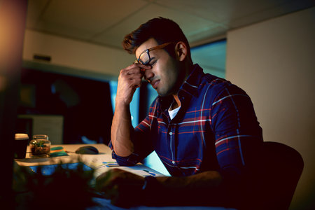 I cant brain tonight. a young businessman experiencing strain during a late night at work.