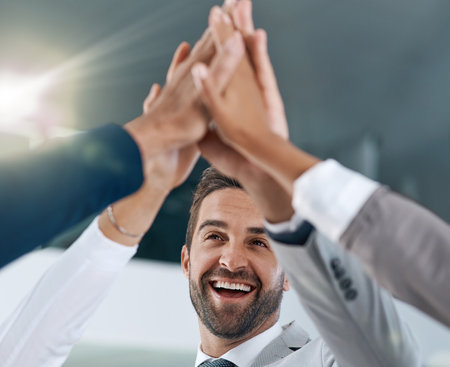 We stand together to make big changes. motivated work colleagues smiling and celebrating with a high five.の写真素材