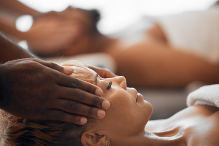 Woman, head massage and couple at beauty spa for facial treatment, wellness and luxury physical therapy for stress relief, zen and calm. Skincare salon therapist, black woman face and relax vacationの写真素材