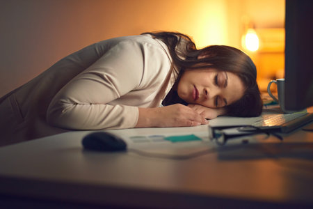 Its not going to be a win tonight. a young businesswoman sleeping at her desk during a late night at work.の写真素材