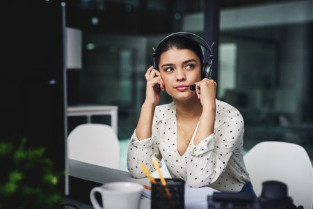 Trying to understand the problem. an attractive young businesswoman looking bored while working late in a call center.の写真素材