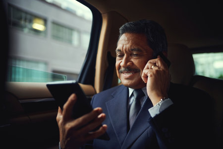 And they said men couldnt multitask. a mature businessman using a phone and digital while traveling in a car.の写真素材