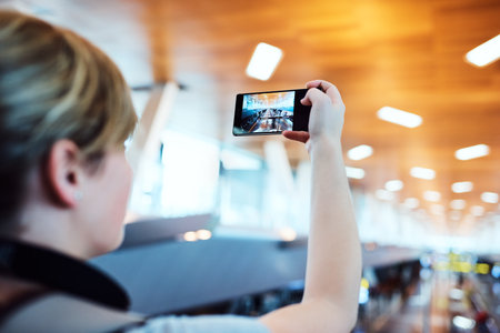 Taking photos wherever she goes. an unrecognizable woman taking photos inside an airport.の写真素材