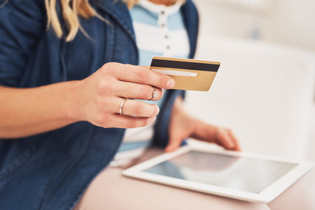 Making online purchases has never been more convenient. Closeup shot of a woman making a credit card payment on a digital tablet at home.の写真素材