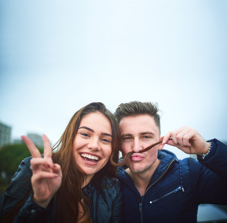 We feel in love with each others weirdness. a happy young couple sharing a playful moment outdoors.の写真素材
