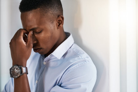 Careful thought is needed in high pressure situations. a young and stressed businessman suffering from a headache while trying to work in the office.の写真素材
